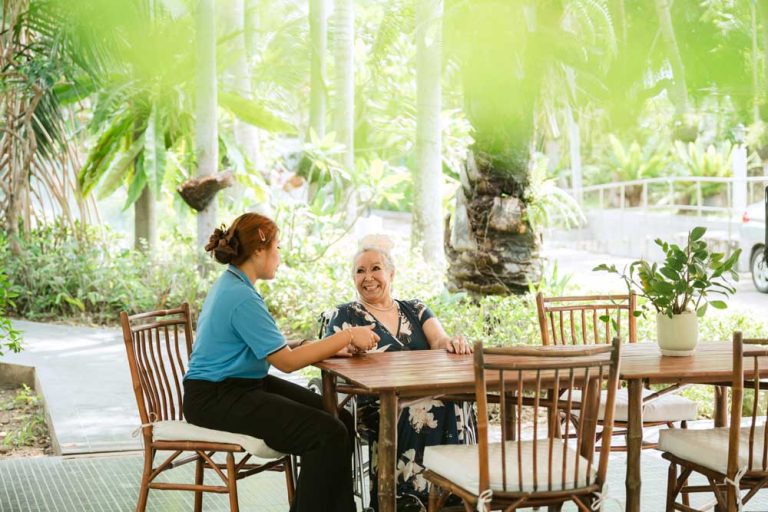 Caring nurse providing gentle wheelchair assistance to happy senior resident