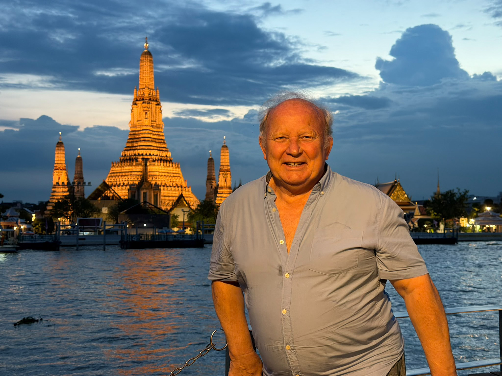 Homerly resident standing along the Chao Phraya River with Wat Arun illuminated in the background