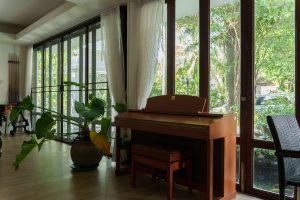Common lounge area at Homerly with a piano and garden view, a quiet space where residents and visiting family can spend time together