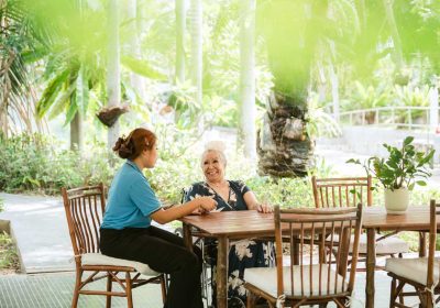 Caring nurse providing gentle wheelchair assistance to happy senior resident